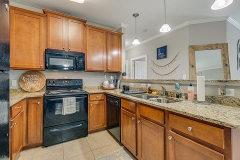 a kitchen with black appliances and granite counter tops and wooden cabinets